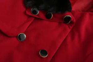 Detalle del cuello de piel sintética negra y botones en un abrigo de lana roja.