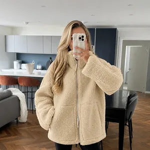 Detail van een beige sherpa fleece coltrui jas in een moderne woonkameromgeving