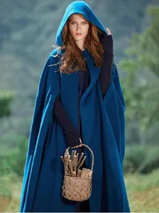 Elegante vrouw in een lange blauwe wollen mantel met capuchon in een bosrijke omgeving