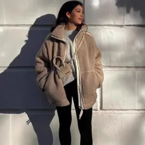 Detailweergave van een gezellig beige oversized fleecejack gedragen door een model buiten