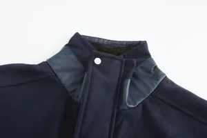Close-up detail of navy blue wool coat collar with leather panels and snap button