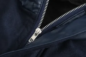 Macro detail of a metallic zipper on a navy blue faux shearling wool coat for men.
