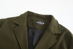 Detail view of the notch lapel and brand label of a men's olive green woolen coat