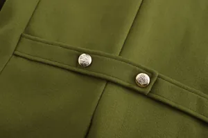 Close-up of decorative silver crest buttons on back strap of olive green wool coat