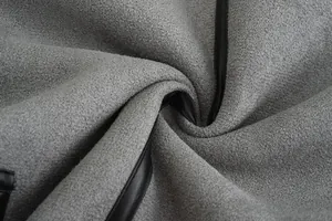 Macro-detailweergave van de zachte grijze lamswoltextuur en de zwarte lederen bies