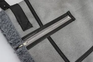 Detailopname van metalen rits en lederen bies op grijze lammy coat jasje