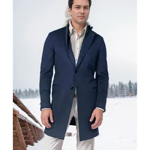 Mittellanger dunkelblauer Herren-Wollmantel, getragen von einem Model im verschneiten Freien.