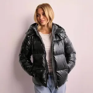 Detail view of a shiny black hooded puffer jacket worn by a model in a casual setting