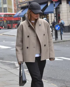 Detail van een beige wollen jas met dubbele rij knopen in Londense streetstyle.