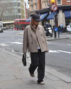 Elegante vrouw in Londen die een beige wollen jas met dubbele rij knopen en zwarte broek draagt