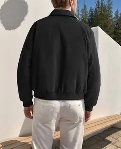 Rear view of a minimalist black zip-up lapel jacket for men in a clean outdoor setting