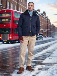 Man wearing a navy wool jacket with fur collar in a snowy urban street setting