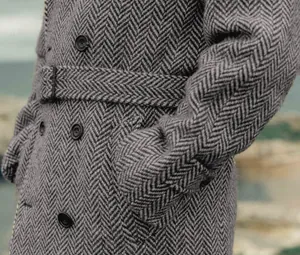 Détail d'un manteau en laine à chevrons gris montrant la ceinture et les boutons.