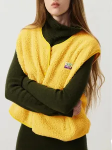 Détail du gilet en polaire sherpa jaune avec fermeture à boutons sur col roulé vert
