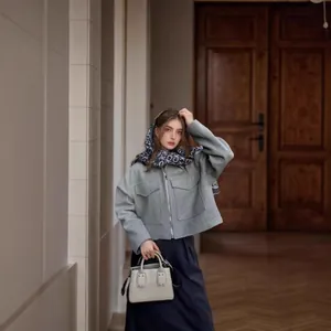 Mannequin portant une veste en laine grise à grandes poches et une écharpe bleue à motifs.