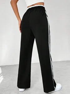 Back view detail of black wide-leg sweatpants with white side stripes and ruffled waist