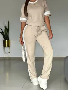 Dettaglio set casual beige due pezzi con strisce laterali bianche su maniche e pantaloni.