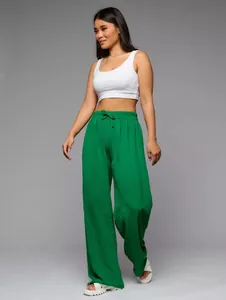 Close-up detail of green wide-leg high-waist casual trousers on a model in grey studio