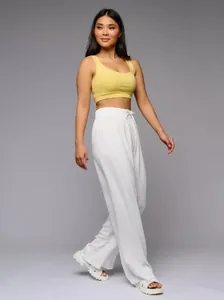 Full-length view of women's white high-waisted wide-leg trousers with flowy textured fabric