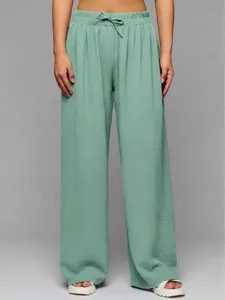 Detail of sage green high-waisted wide-leg trousers with drawstring and textured fabric