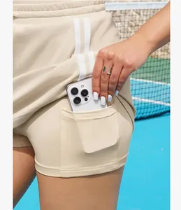 Close-up detail van de functionele binnenzak op een beige tennisrok met een smartphone