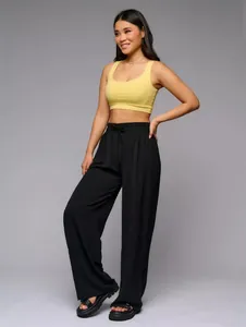 Woman wearing black high waisted wide leg trousers and yellow cropped tank top
