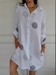 Detail view of a white shirt dress with grey polka dot print and button closure