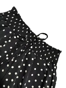 Close-up of bohemian black polka dot wide-leg pants featuring a smocked elastic waist.