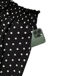 Detail view of polka dot wide-leg pants featuring a functional side pocket with a smartphone