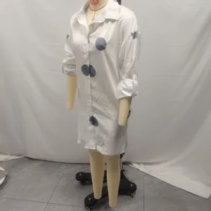 Detailed view of white long-sleeve shirt dress with large grey polka dot print pattern