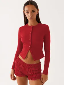 Detail view of a slim fit red ribbed long sleeve cardigan buttoned over ruffled shorts.