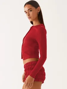 Detailed side view of a red ribbed knit cropped cardigan and matching ruffled shorts