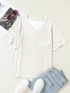 Dettaglio macro della maglia bianca a coste con scollo a V, tasca e oggetti di scena