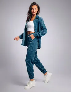 Full body view of a woman modeling a teal corduroy leisure set with an oversized shirt