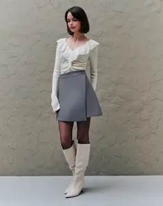 Detalle de falda cruzada gris de talle alto con diseño asimétrico para mujer.