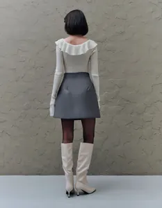 Vista trasera de falda gris de corte en A de talle alto con top de punto blanco y botas