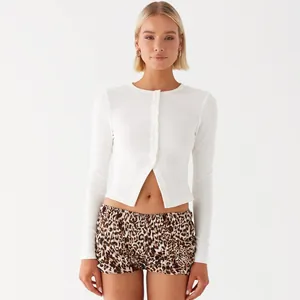 Model wearing a white ribbed long-sleeved button-up cropped cardigan with leopard shorts
