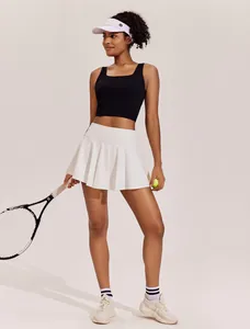 Detail van de witte geplooide tennisrok op een model met een tennisracket erbij.