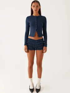 Full body view of a navy blue ribbed long sleeve cardigan paired with ruffled shorts