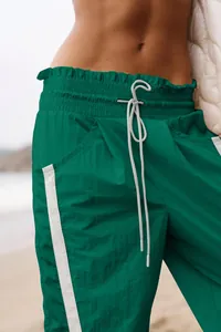 Close-up of green high-waisted jogger pants with white drawstring and side stripes