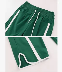 Close-up detail of green sweatpants with elastic drawstring waist and split hem