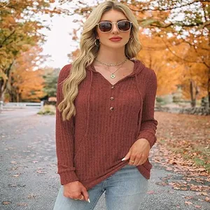 Détail d'un pull à capuche bordeaux pour femme avec texture côtelée dans un parc d'automne.