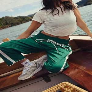 Detail view of green Y2K side-striped sports pants with drawstring waist on a boat