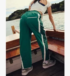 Outdoor view of green high-waisted sports pants with white side stripes for women