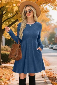 Long sleeve blue ribbed dress with round neck shown in a scenic autumn outdoor setting