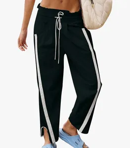 Detailed view of high-waisted black athletic pants with white side stripes and split hem.
