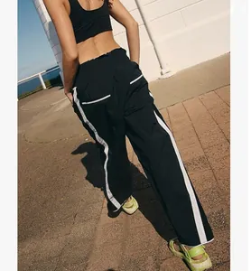 Rear view of black Y2K straight-leg sports pants with white side stripes in outdoor setting