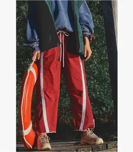 Close-up of red Y2K track pants with white side stripes and drawstring waist detail
