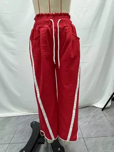 Vibrant red high-waisted drawstring sports pants with white side stripes on a mannequin