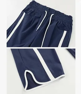 Detailed view of elastic drawstring waist and side slit hem on navy sporty pants